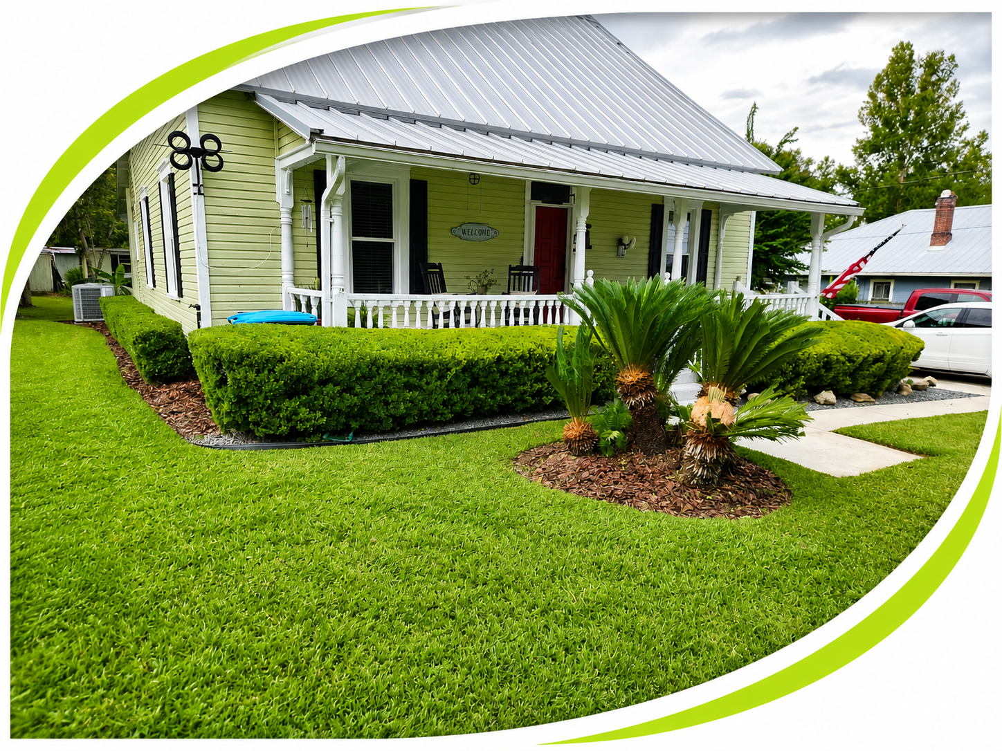 A well-kept farmhouse-style home with a manicured lawn, trimmed hedges, and a sago palm bed