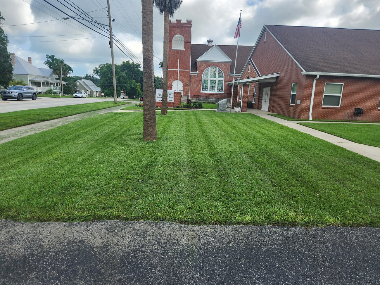 A freshly striped, manicured lawn with mature trees