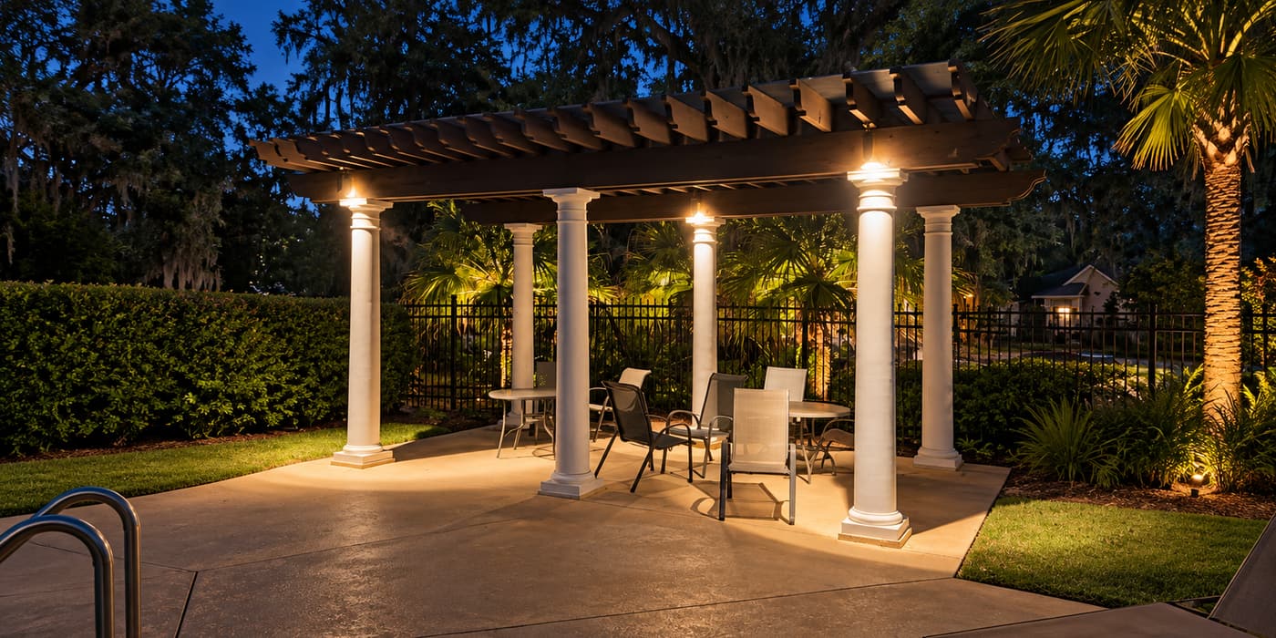 Landscape and pergola lighting illuminating an outdoor patio and garden at dusk