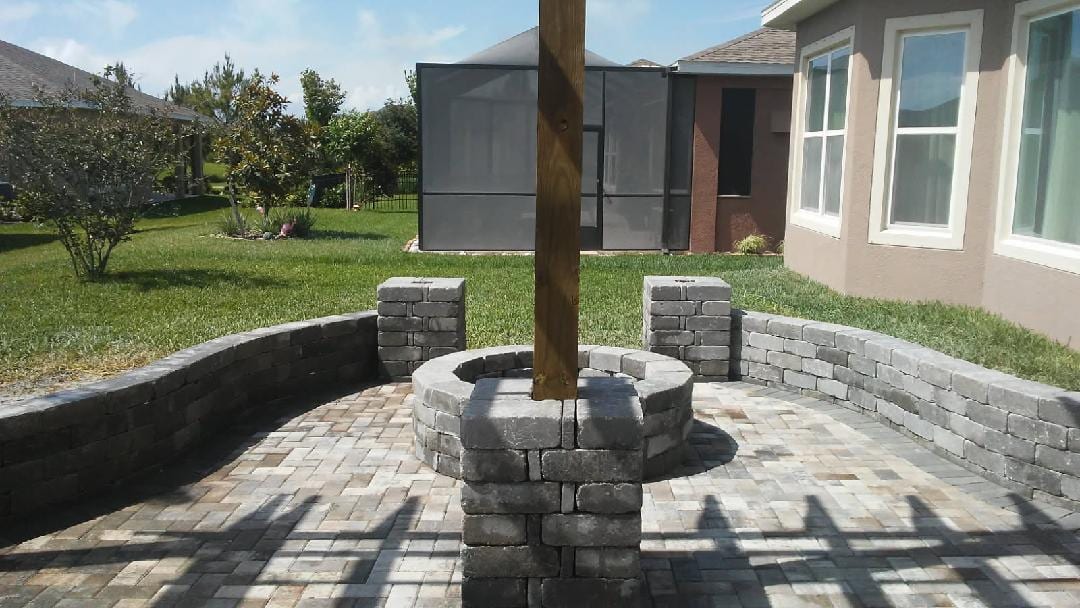 Paver patio with a stacked-stone seat wall and built-in fire pit under a pergola