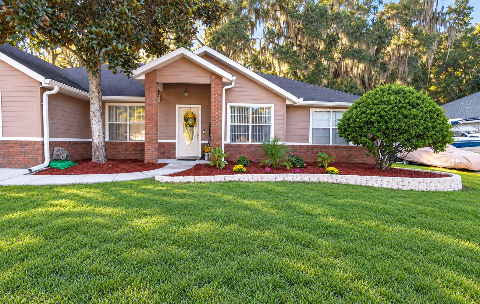 A curved mulch bed with a stone border at a front entry
