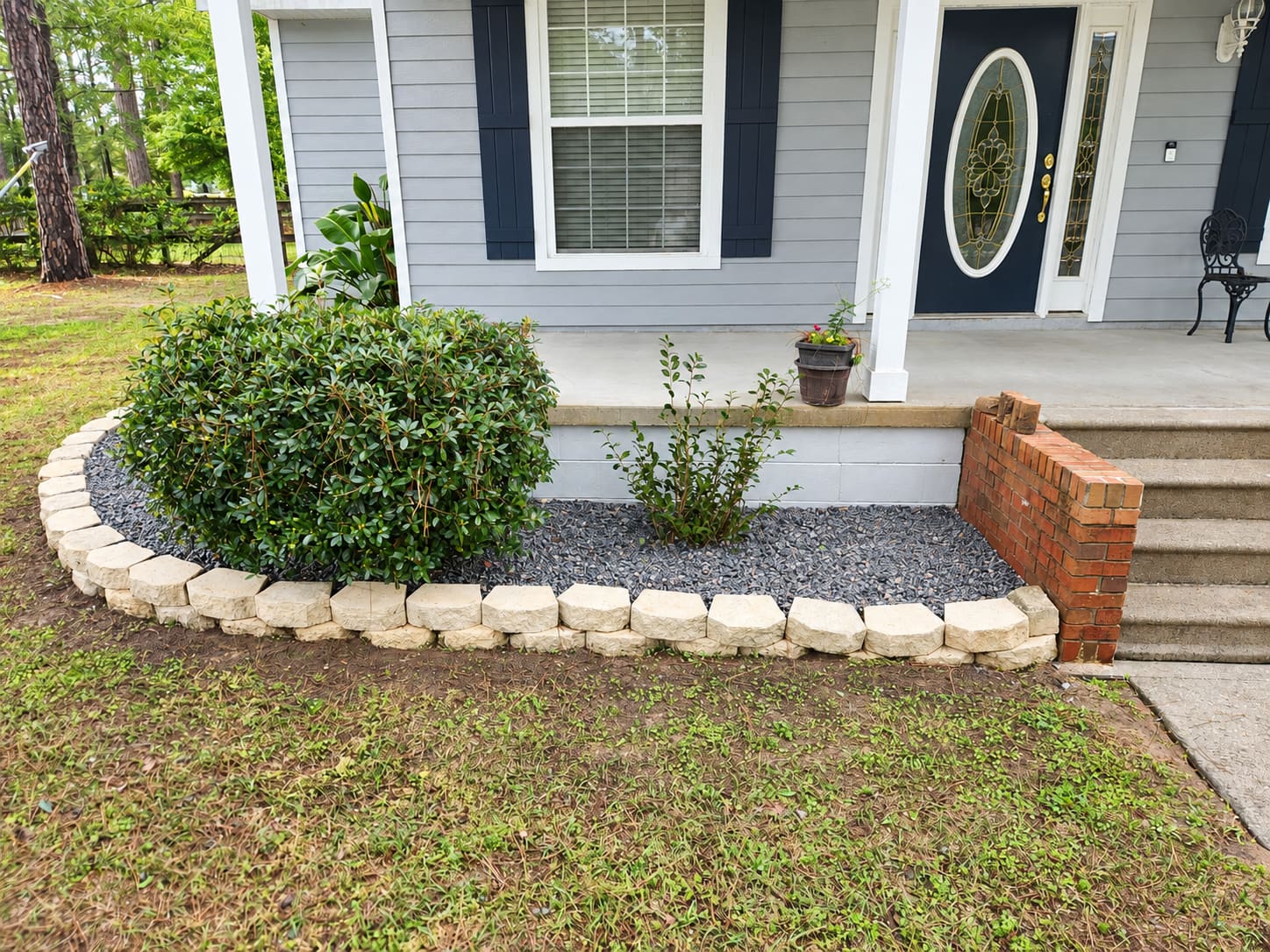 A gravel planting bed with a stone border along front porch steps