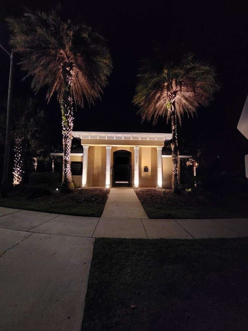 An illuminated clubhouse entrance with landscape lighting