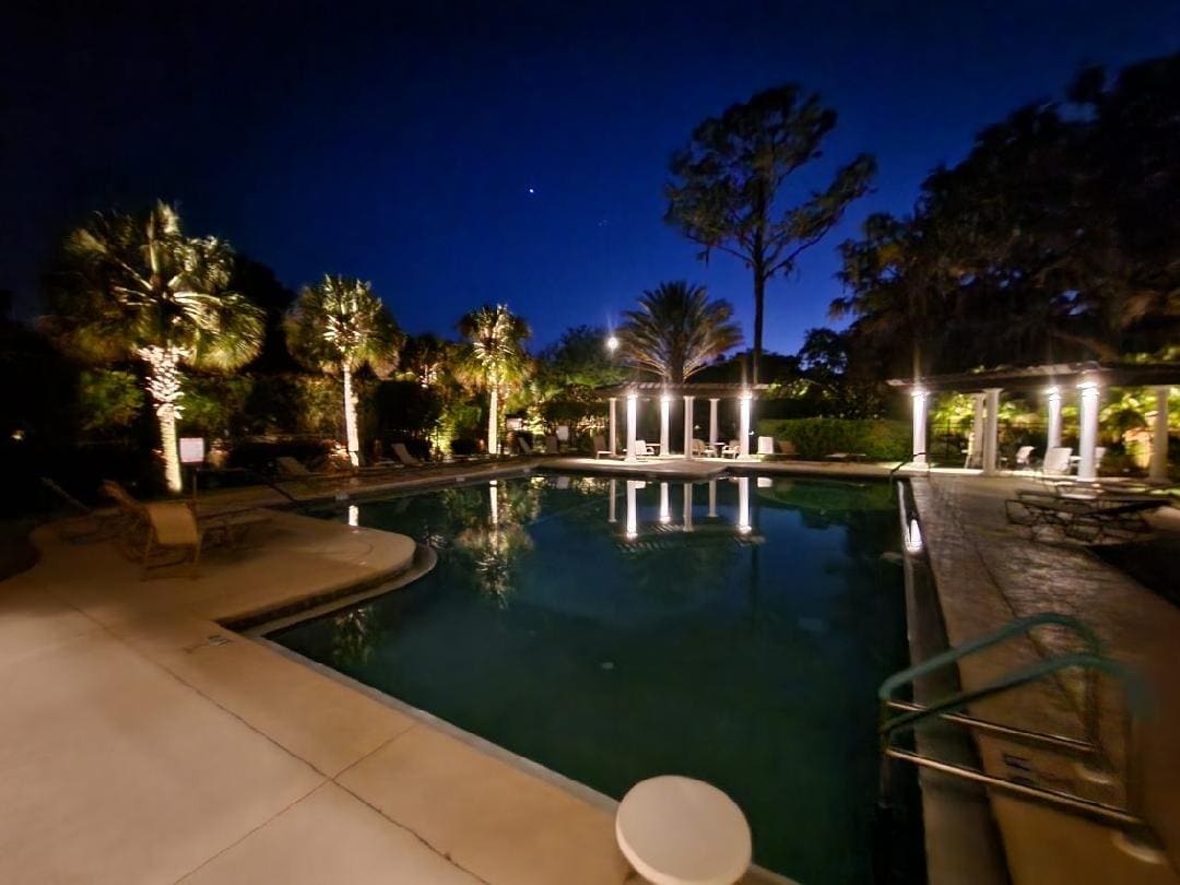 A community pool area with landscape lighting at night