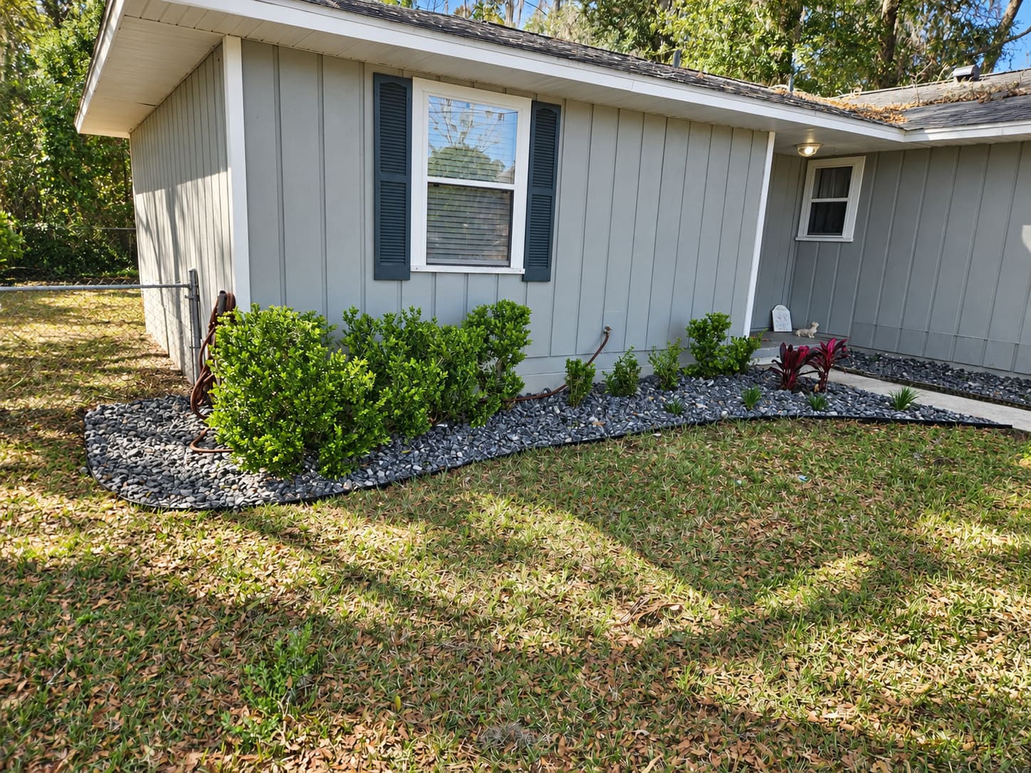 A river rock planting bed with boxwood shrubs along a side yard