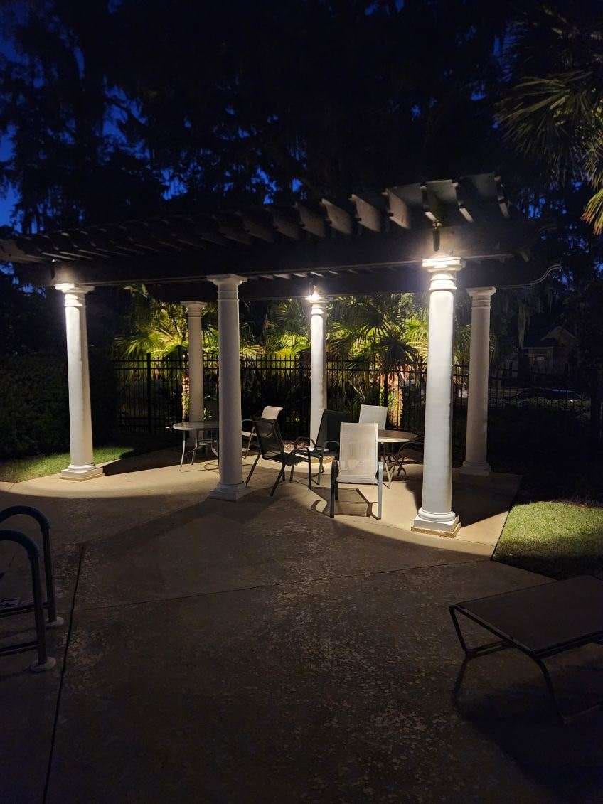 A pergola seating area illuminated with landscape lighting at night