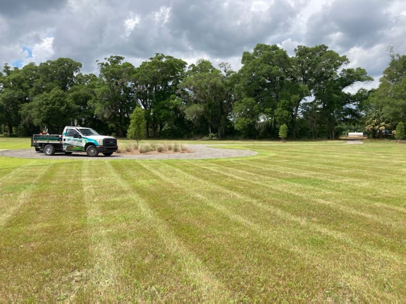 A company truck parked beside a striped, freshly mowed lawn on an open property