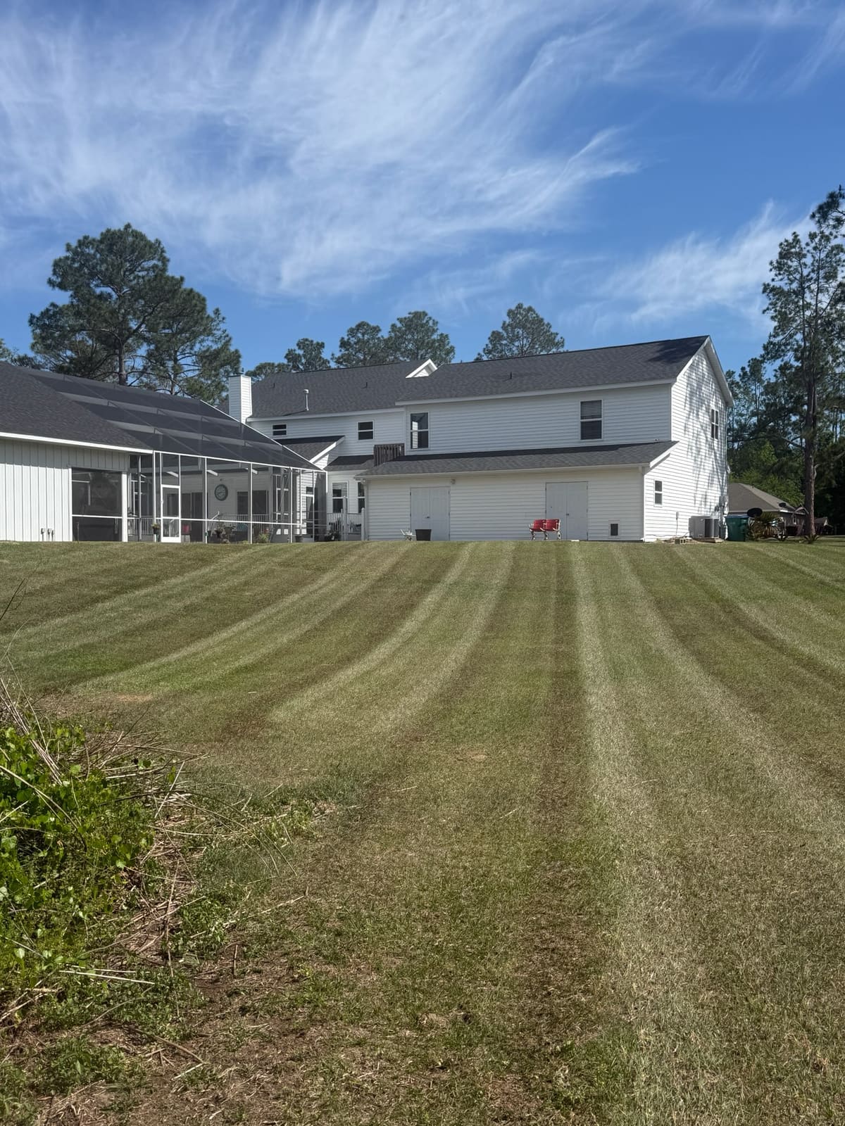 A striped, freshly mowed backyard lawn behind a two-story house