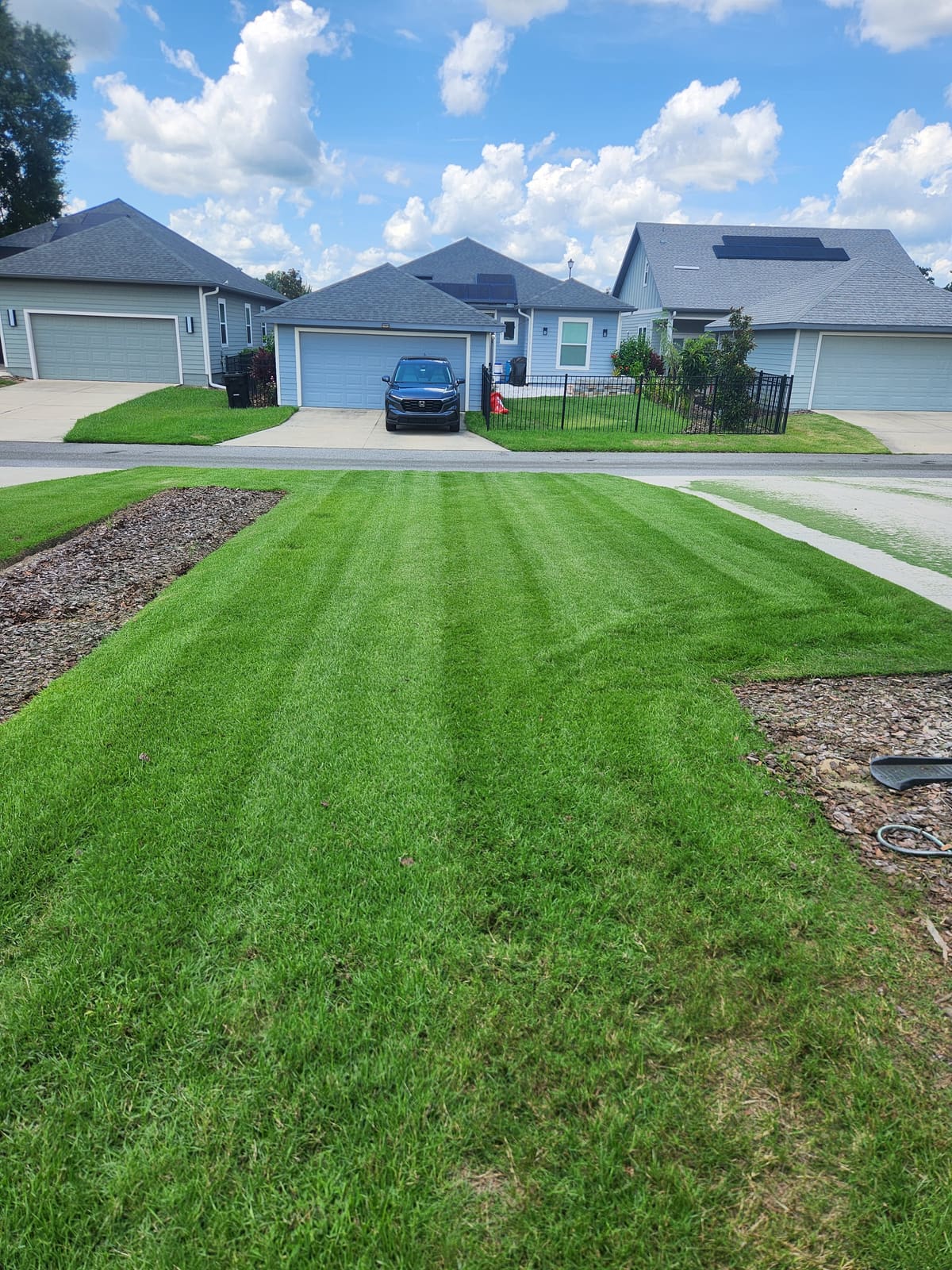 A striped, freshly mowed front lawn in front of a house with a garage